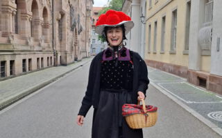 Eine Frau mit „Bollenhut“, im Hintergrund das Freiburger Münster